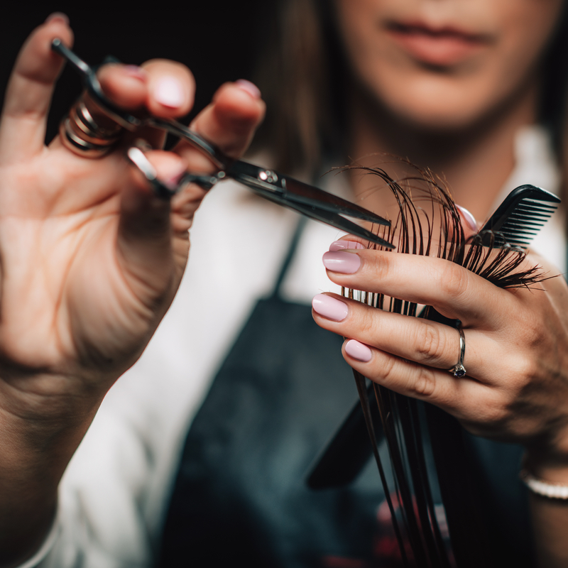 Stylist using professional scissors to cut hair at Salon LáShae